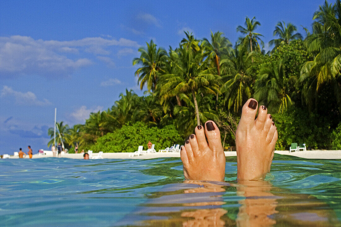 Womens feet, Palm trees at the beach of Biyadhoo Island, Indian Ocean, South Male Atoll, Maldives