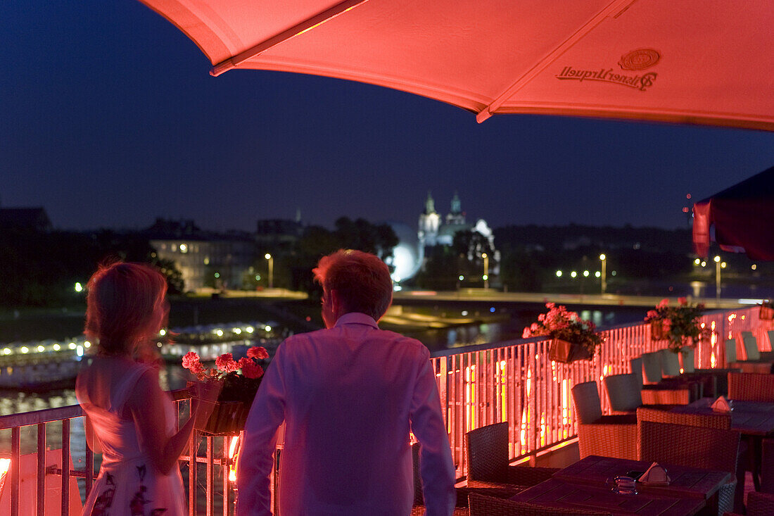 Young couple on the roof terrace of Hotel Poleski at night, Krakow, Poland, Europe
