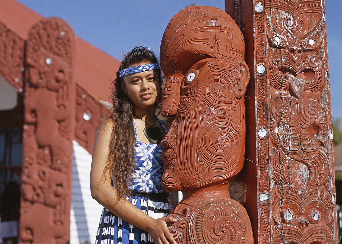 Maori girl beside traditional carvings Ohinemutu Rotorua New Zealand