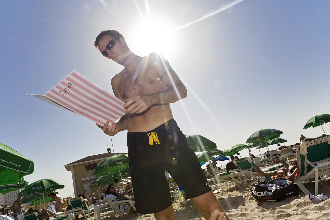 Mann liest die Speisekarte eines Strandcafes, Gordon Beach, Tel Aviv, Israel, Naher Osten