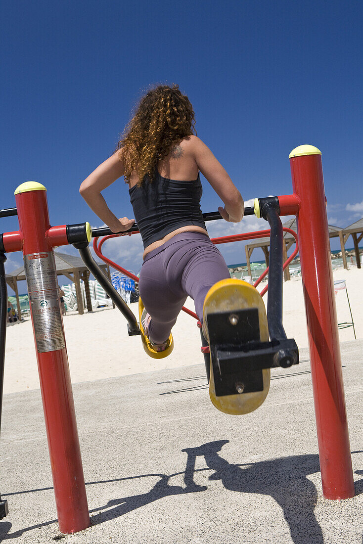 Eine Frau trainiert an einem Sportgerät am Strand, Tel Aviv, Israel, Naher Osten