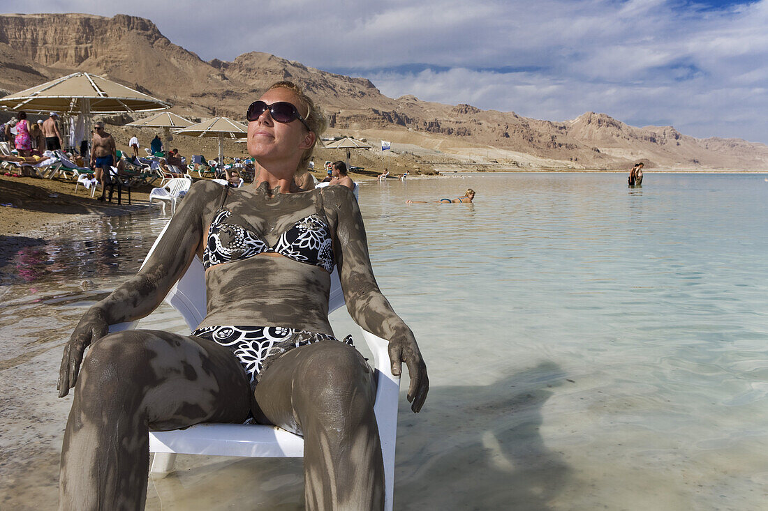 Woman smeared with mineral mud sunbathing, Dead Sea, En Bokek, Israel, Middle East