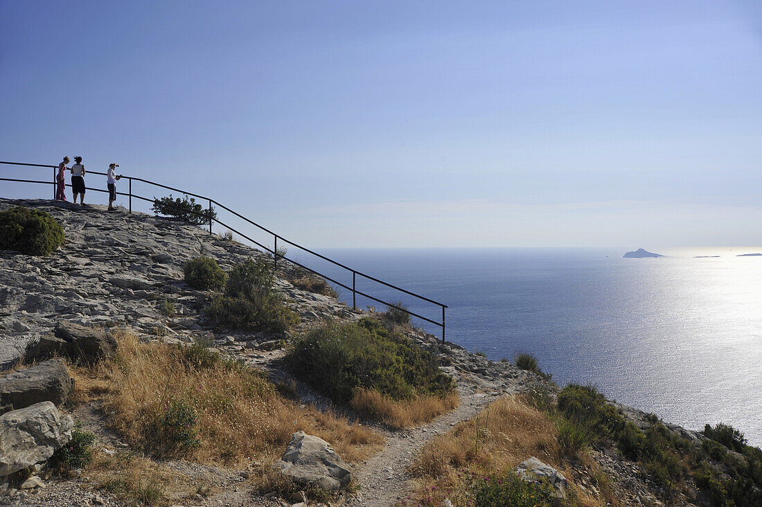 Drei Menschen blicken vom Aussichtspunkt übers Meer, Corniche des Cretes, Cap Canaille, Calanques, Provence, Frankreich, Europa
