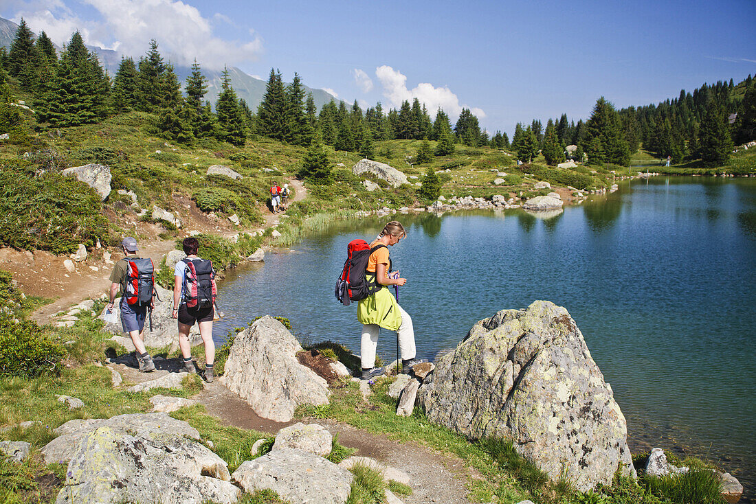 Group hikers near mountain lake, Alp Flix, Canton of Grisons, Switzerland