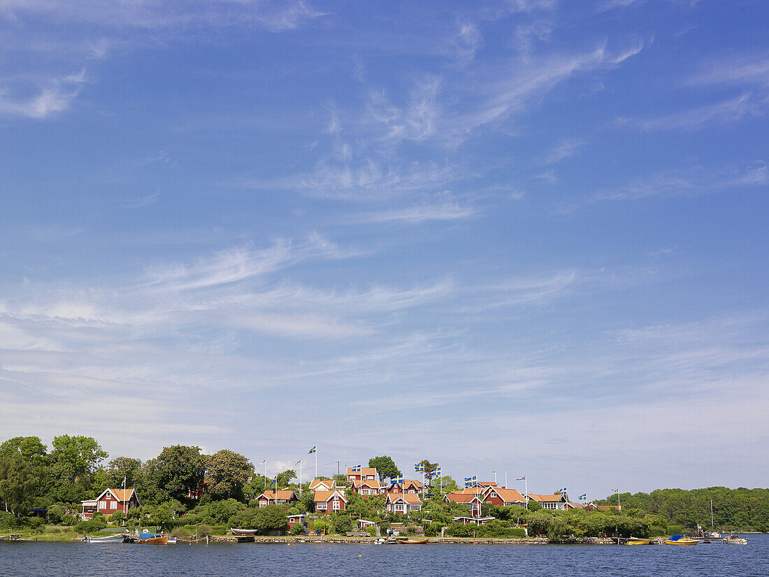 Red houses with Swedish flags in archipelago, Karlskrona, Blekinge, Sweden