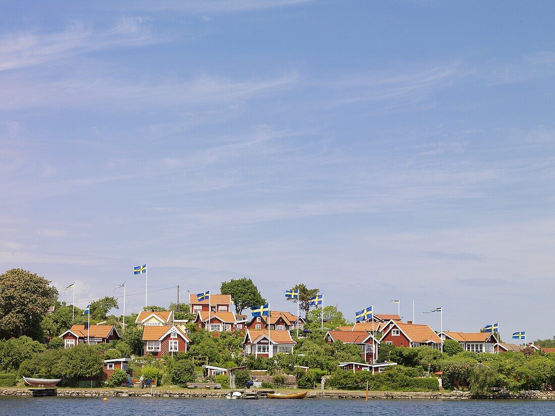 Red houses with Swedish flags in archipelago, Karlskrona, Blekinge, Sweden