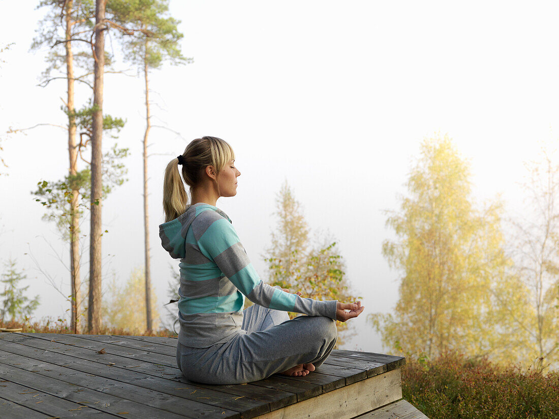 Woman meditates on terrace, Skane, Sweden