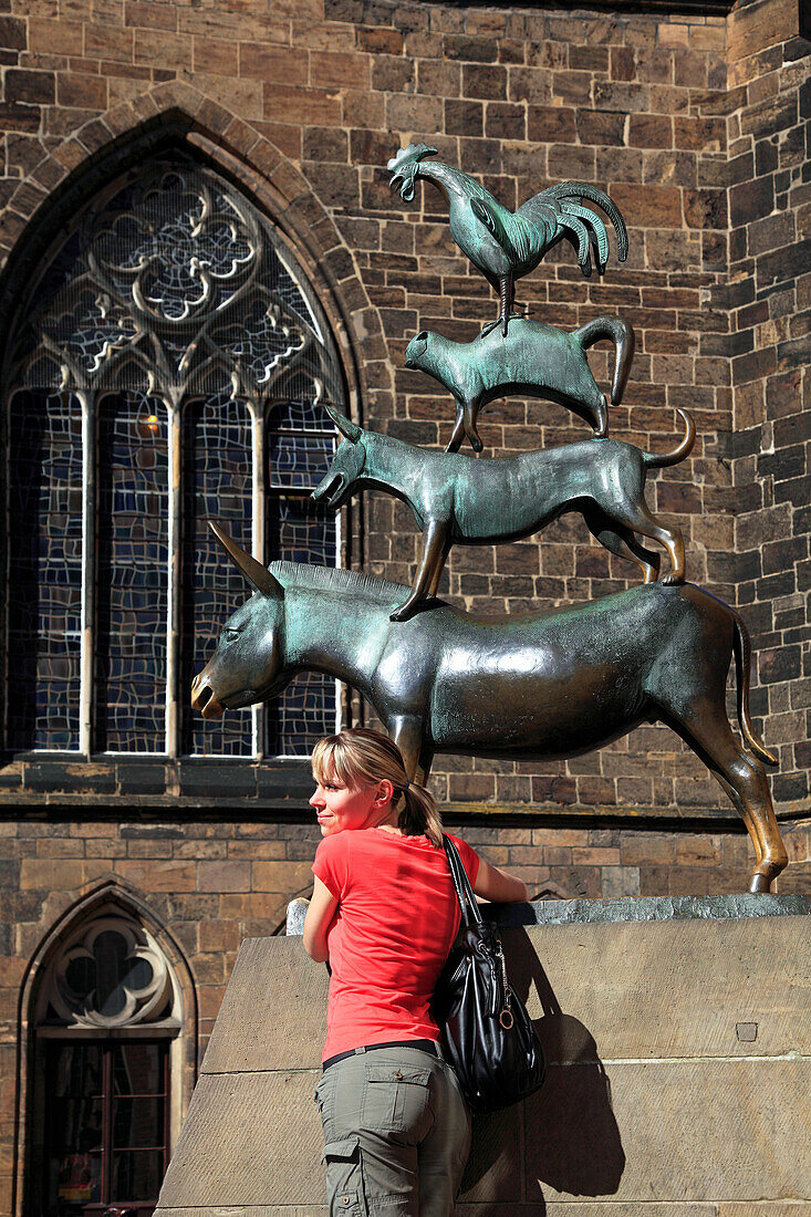 Junge Frau posiert vor den Bremer Stadtmusikanten, Hansestadt Bremen, Deutschland, Europa