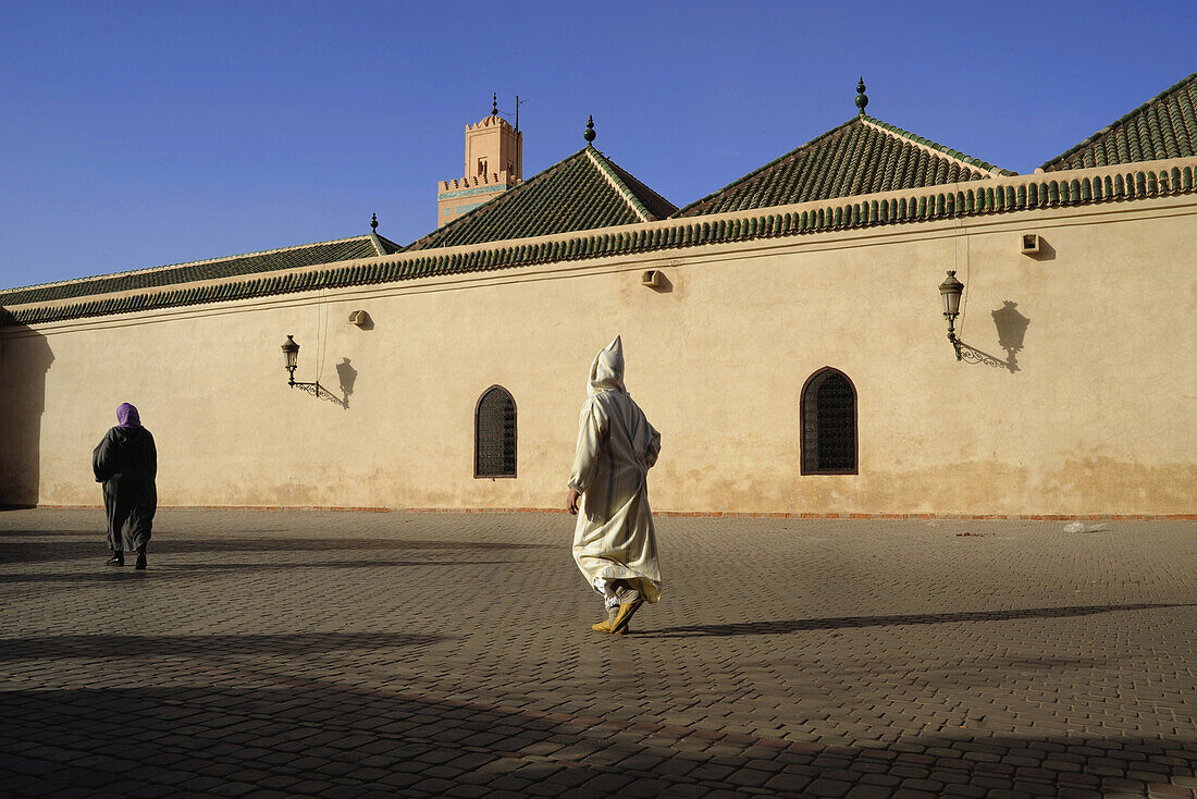 Mann in Djelaba, traditioneller Bekleidung, vor Moschee in Marrakesch, Marokko, Afrika