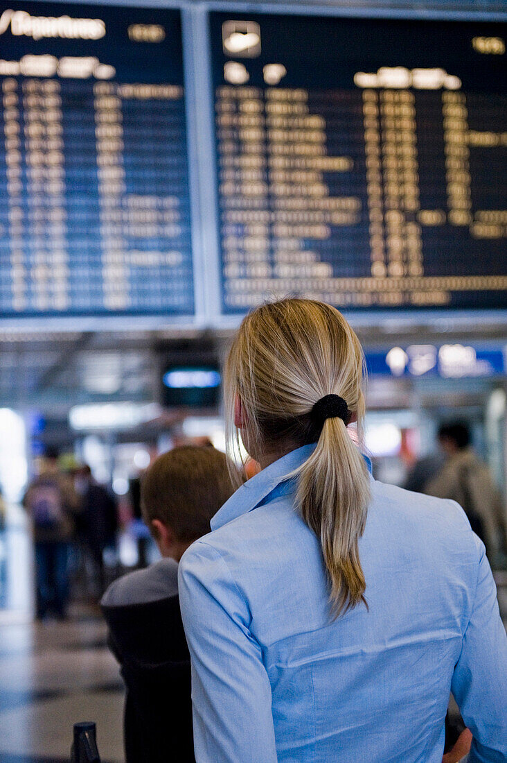 Woman reading flight-information board, Munich airport, Bavaria, Germany