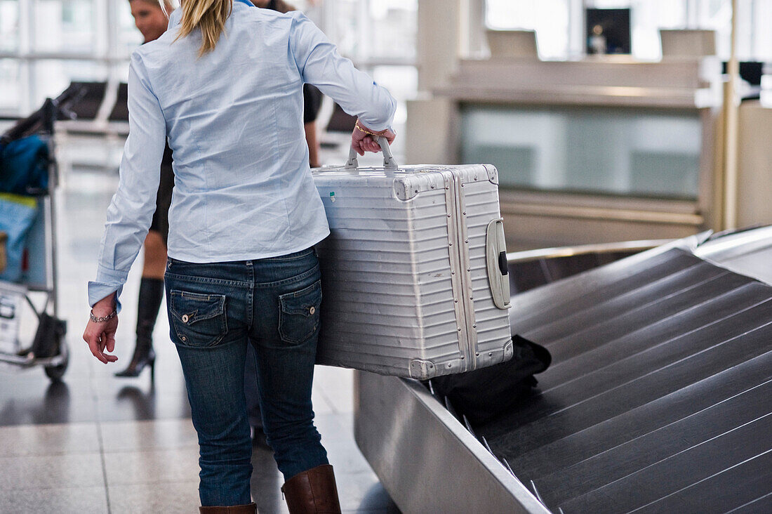 Frau nimmt Koffer von Gepäckband, Flughafen München, Bayern, Deutschland