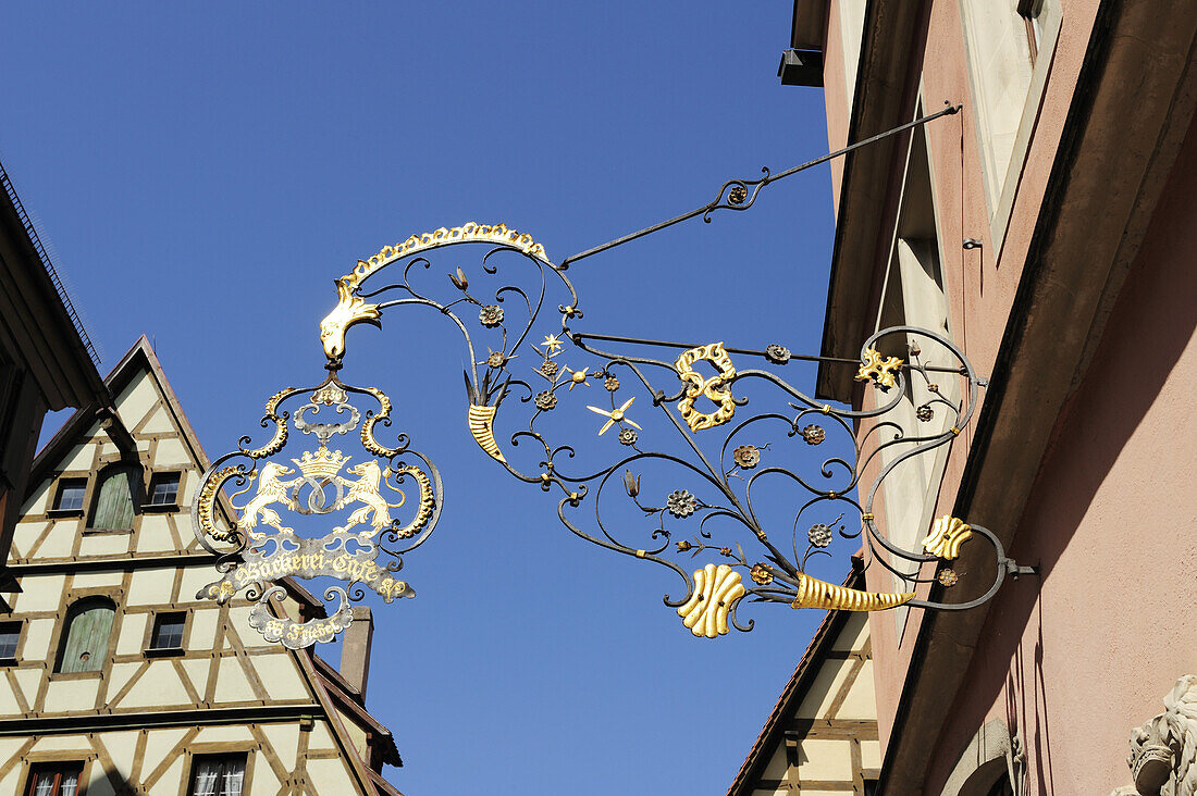 Wrought iron guild sign in front of  a half-timbered house, Rothenburg ob der Tauber, Bavaria, Germany