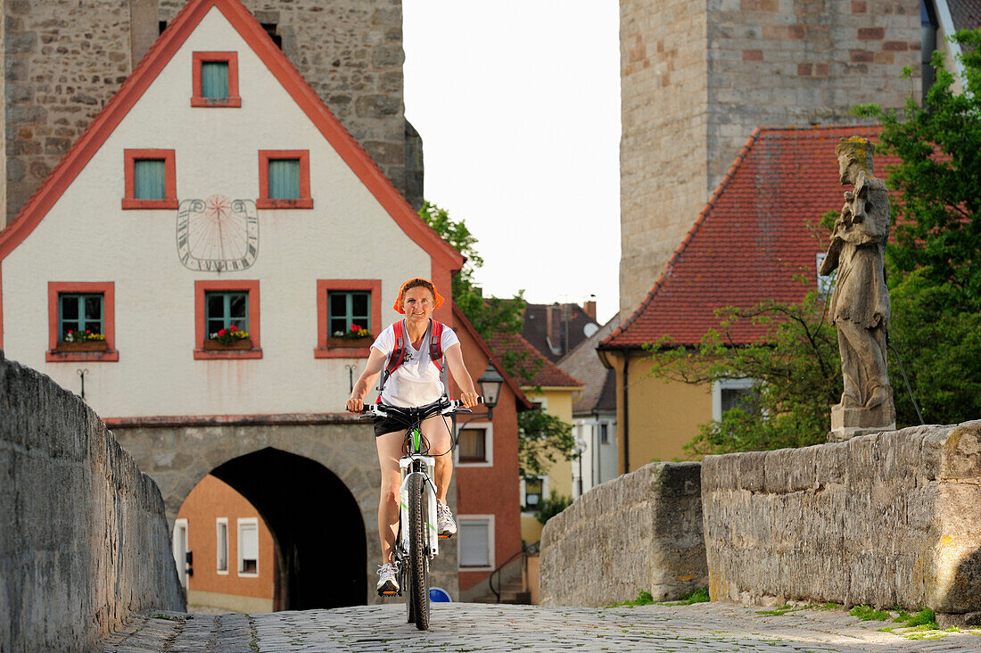 Radfahrerin fährt über Brücke, Stadttor im Hintergrund, Ornbau, Altmühltal-Radweg, Bayern, Deutschland