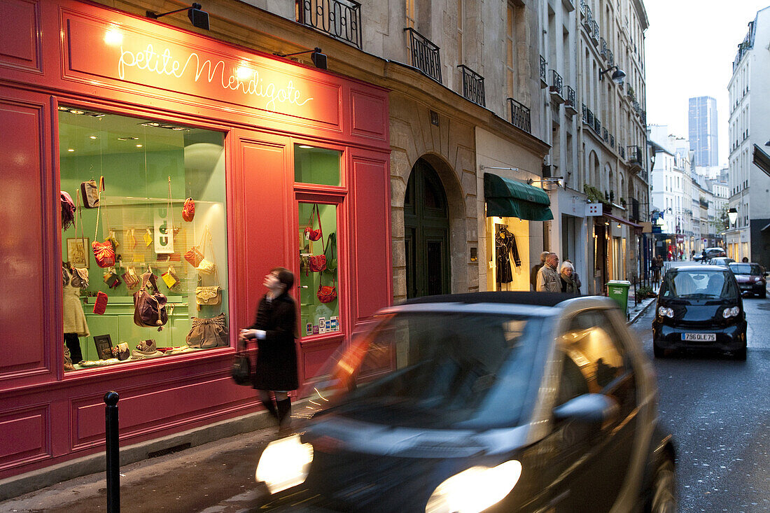 Woman in front of illuminated shop window in the evening, 7th arrondissement, Paris, France, Europe