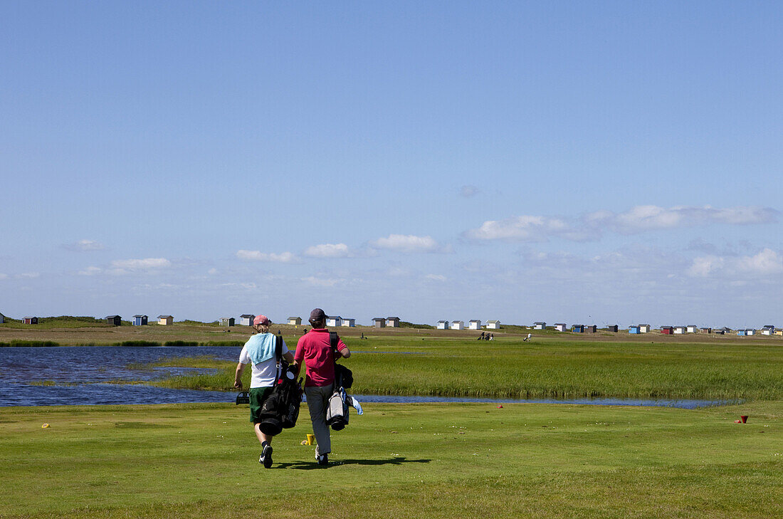 Golfer auf dem Golfplatz von Falsterbo mit Strandhäuschen im Hintergrund, Falsterbo, Skanör, Schonen, Südschweden, Schweden