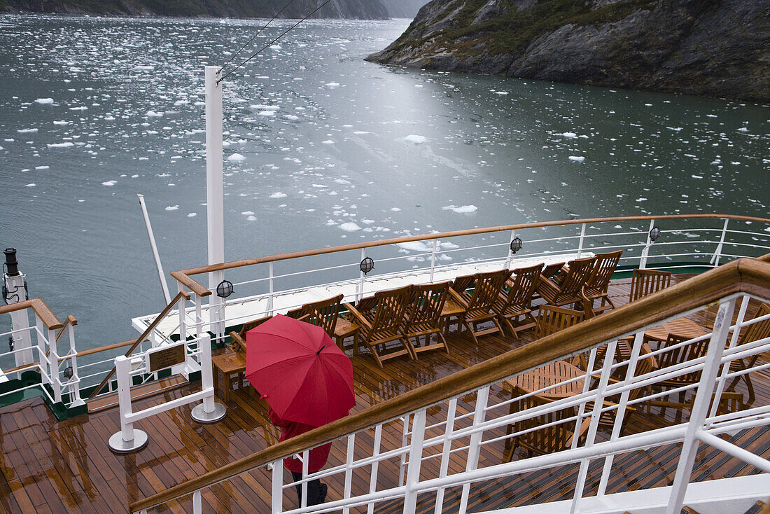 Mann mit rotem Regenschirm auf Deck von Kreuzfahrtschiff MS Deutschland (Reederei Deilmann), nahe Garibaldi Gletscher, Chilenische Fjorde, Beagle Kanal, Patagonien, Chile, Südamerika, Amerika