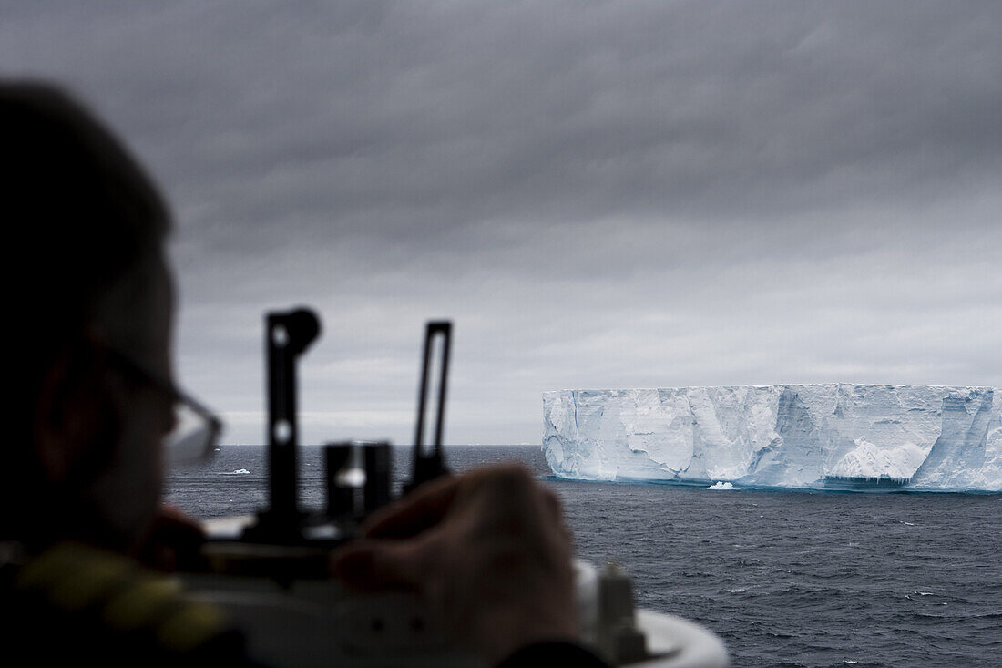 MS Deutschland Staff Kapitän Elmar Mühlebach stellt mit Sextanten die Größe eines antarktischen Eisberges fest, Südliche Shetlandinseln, Antarktis