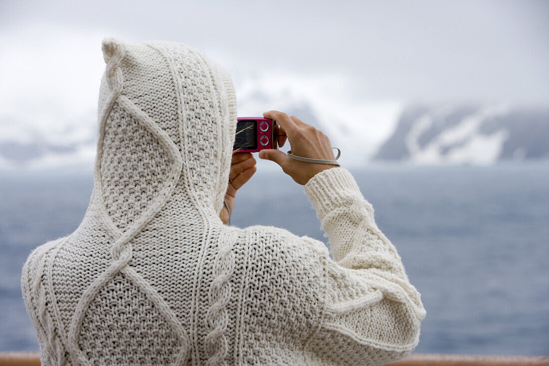 Frau mit Kapuzenpullover fotografiert Landschaft vom Deck von Kreuzfahrtschiff MS Deutschland (Reederei Deilmann), Südliche Shetlandinseln, Antarktis