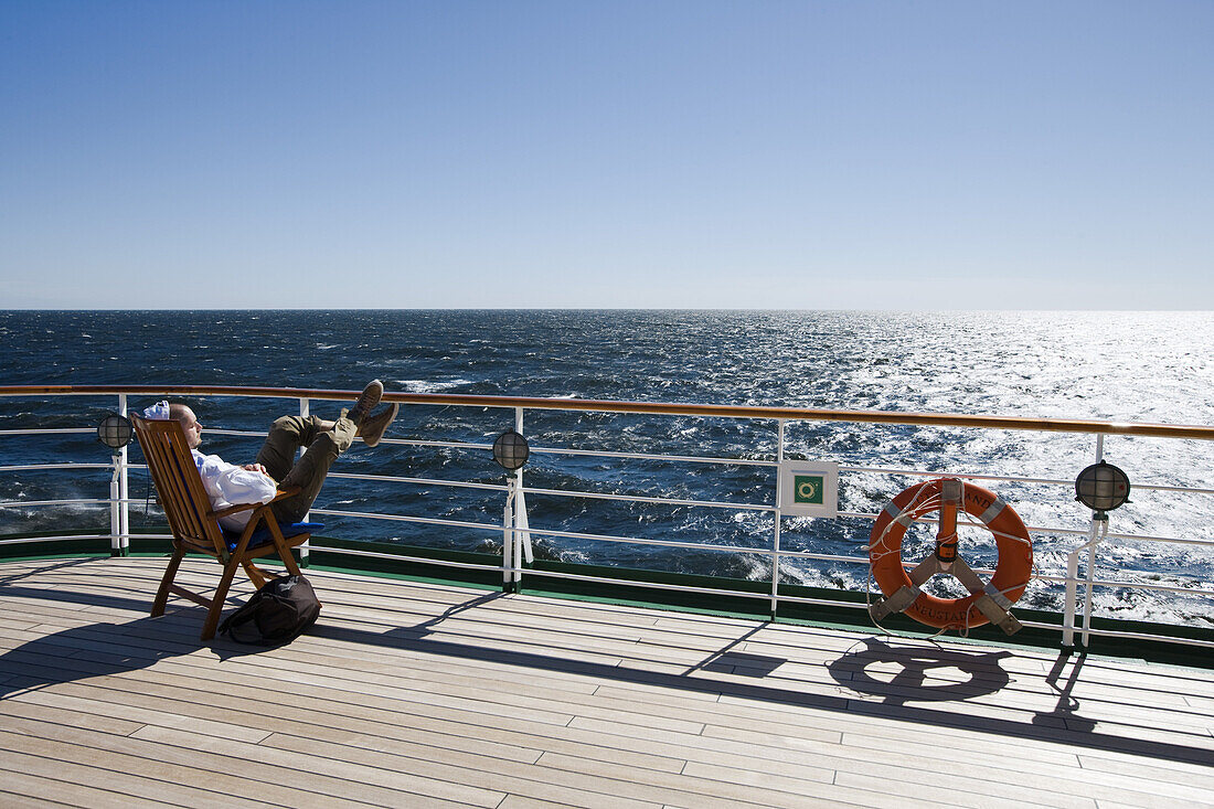 Mann im Liegestuhl an Deck von Kreuzfahrtschiff MS Deutschland (Reederei Deilmann), im Südatlantik, Südamerika, Amerika