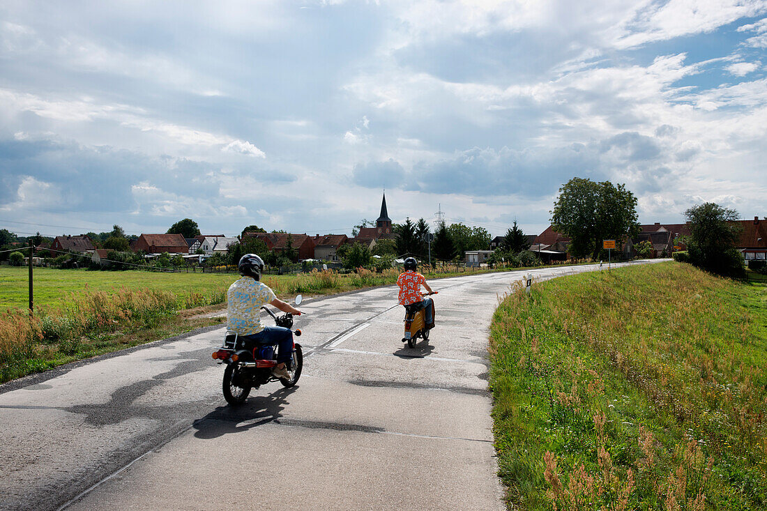 Moped driver heading towards a village, Baelow, Elbetal National Park, Prignitz, Land Brandenburg, Germany
