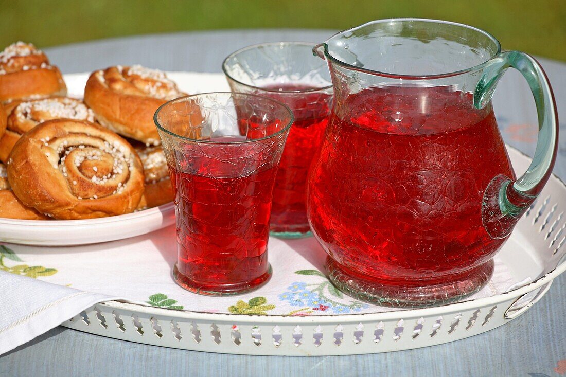 Zimtschnecken und gläserner Krug mit Saft auf einem Tablett