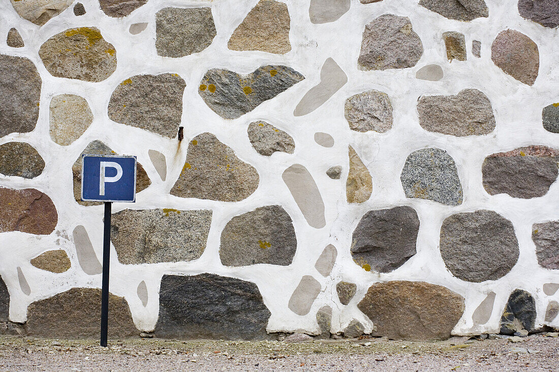 Steinmauer und Parkplatz Schild