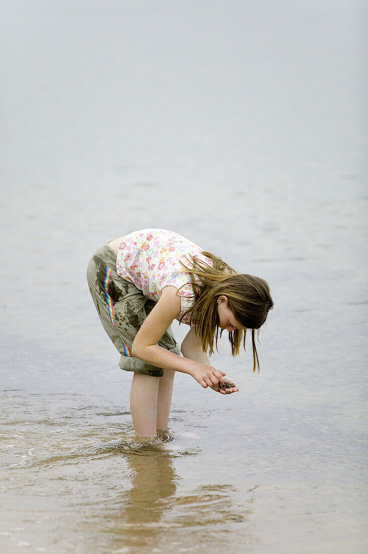 Girl is looking for stones in the water´s edge