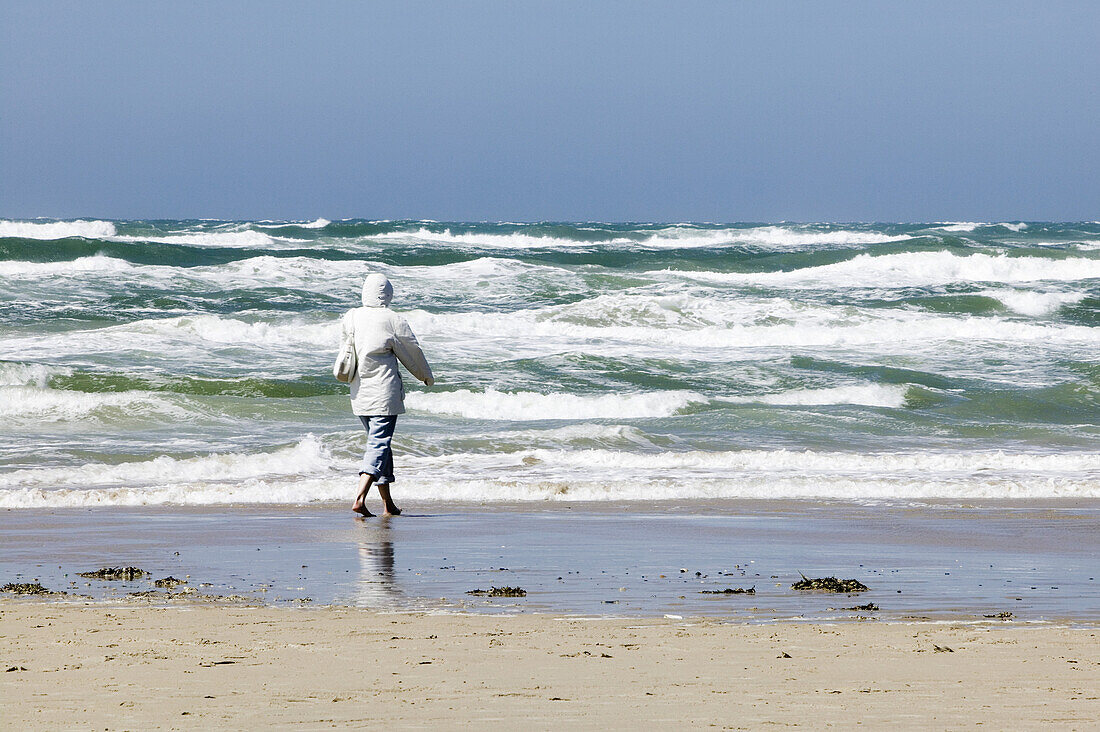 Woman walks on beach, stormy weather, Jutland, Denmark