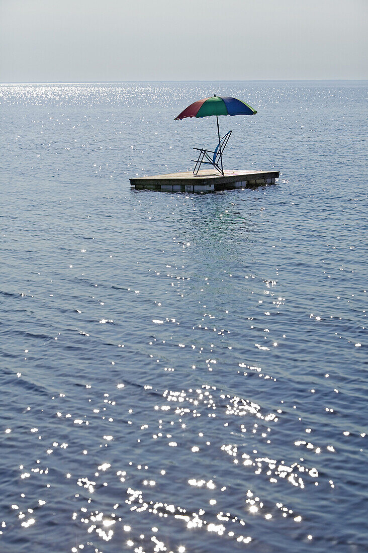 Chair and umbrella on raft in the sea