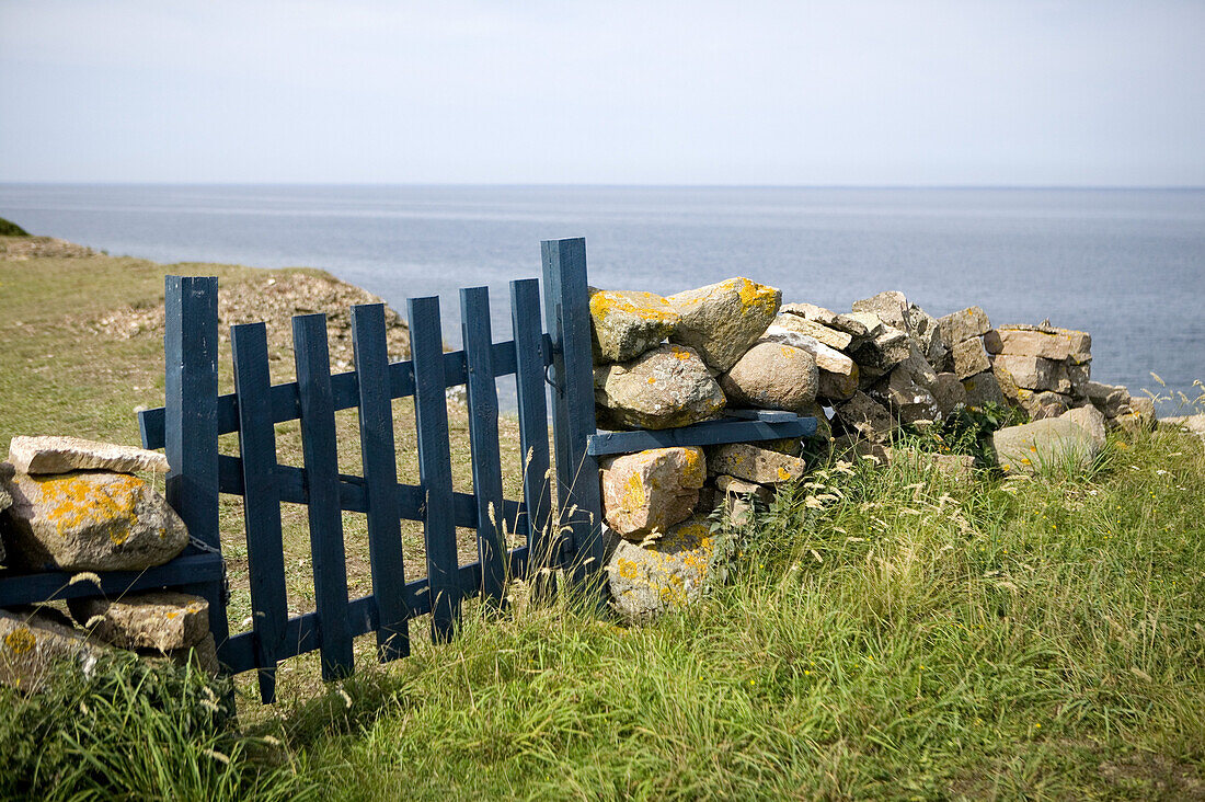 Blue fence and a stone wall at the sea