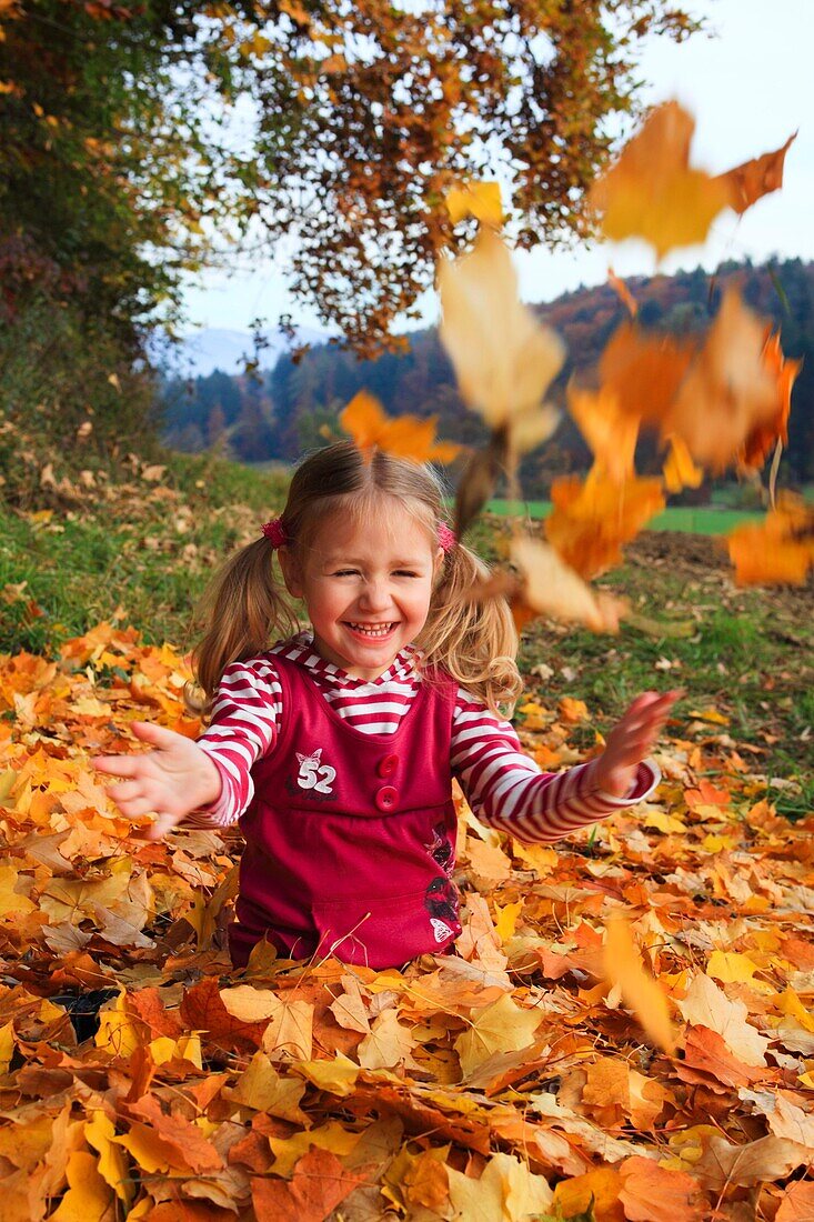 girl playing in pile of leaves, fall Zuerich, Switzerland
