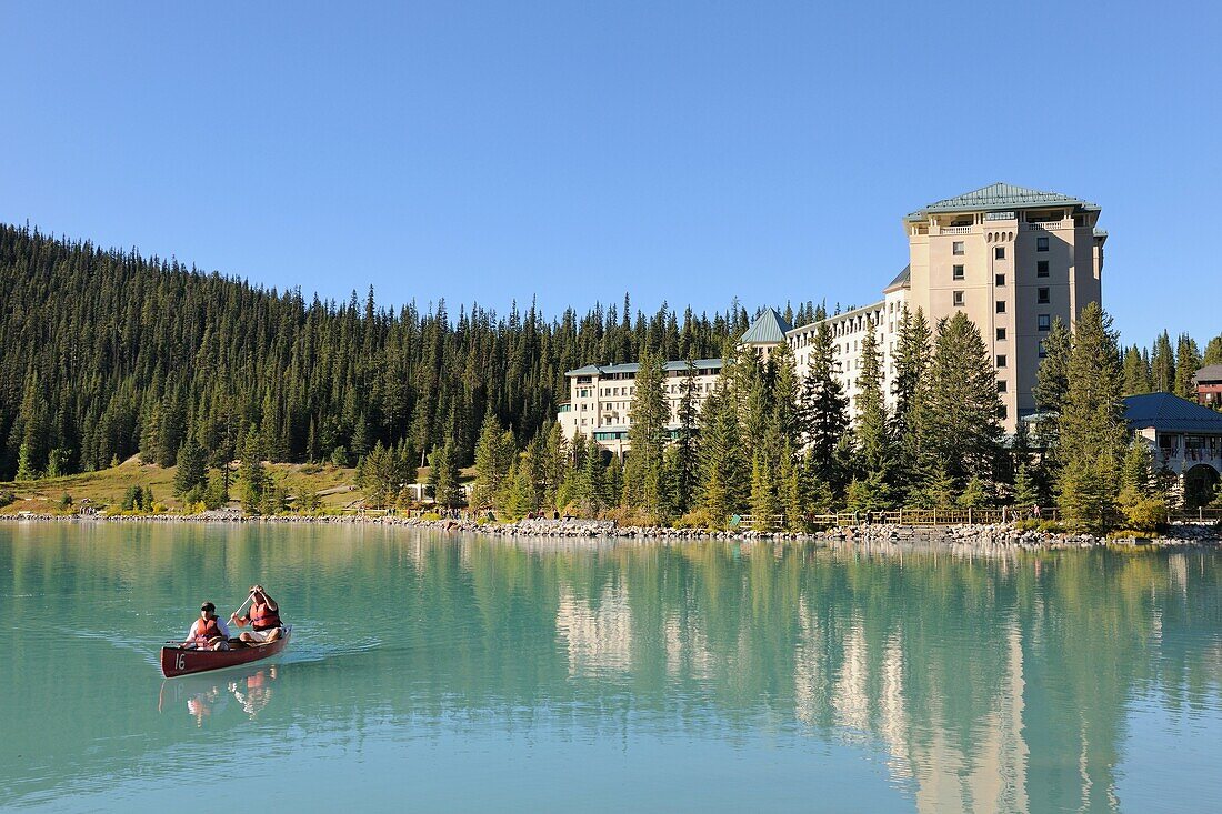 Couple in canoe in front of the hotel Castle Lake Louise, Banff National Park, Rocky Mountains, Alberta, Canada