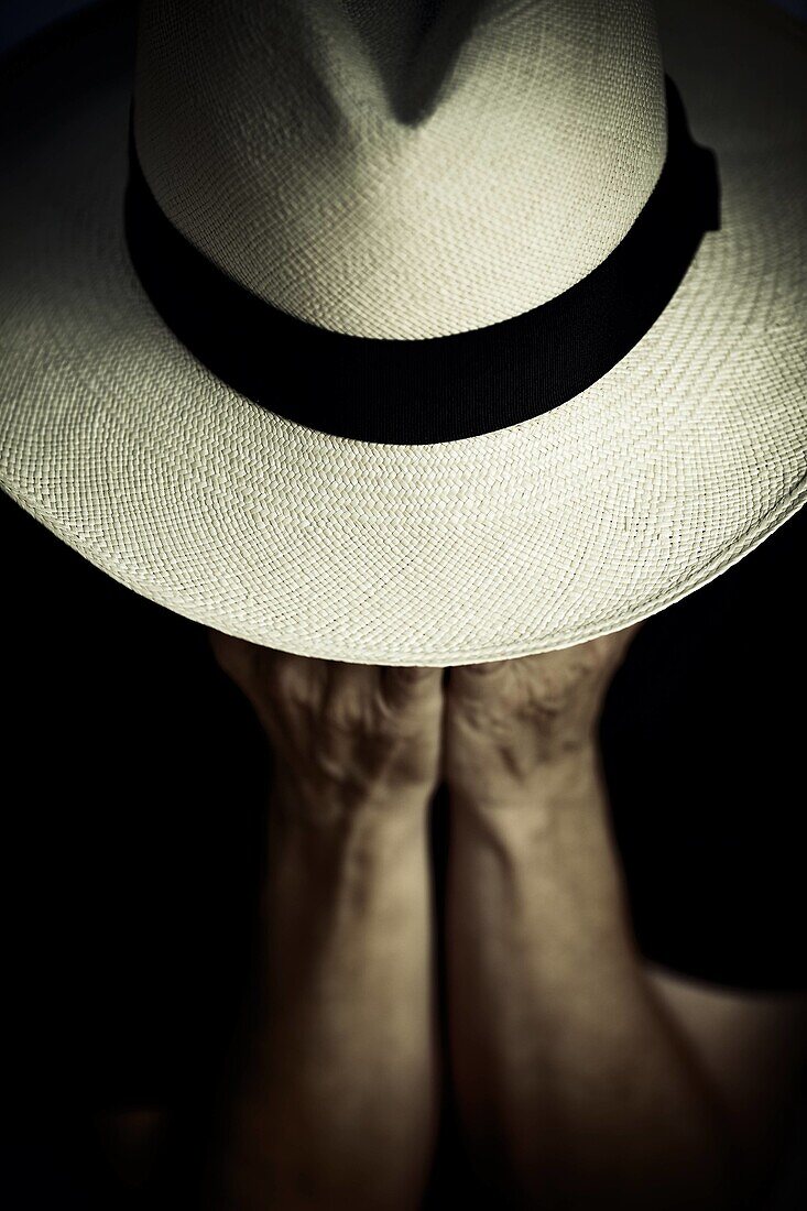A woman ismeditating under his Panama hat