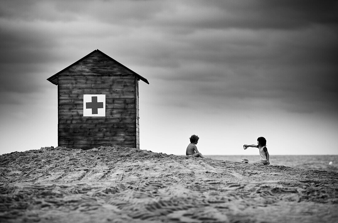 Children playing on the beach next to the hut of the Red Cross