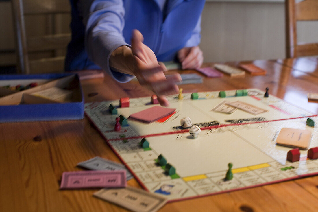 Frau beim würfeln, Monopoly-Spiel mit Würfeln, Häusern und Spielgeld, Deutschland