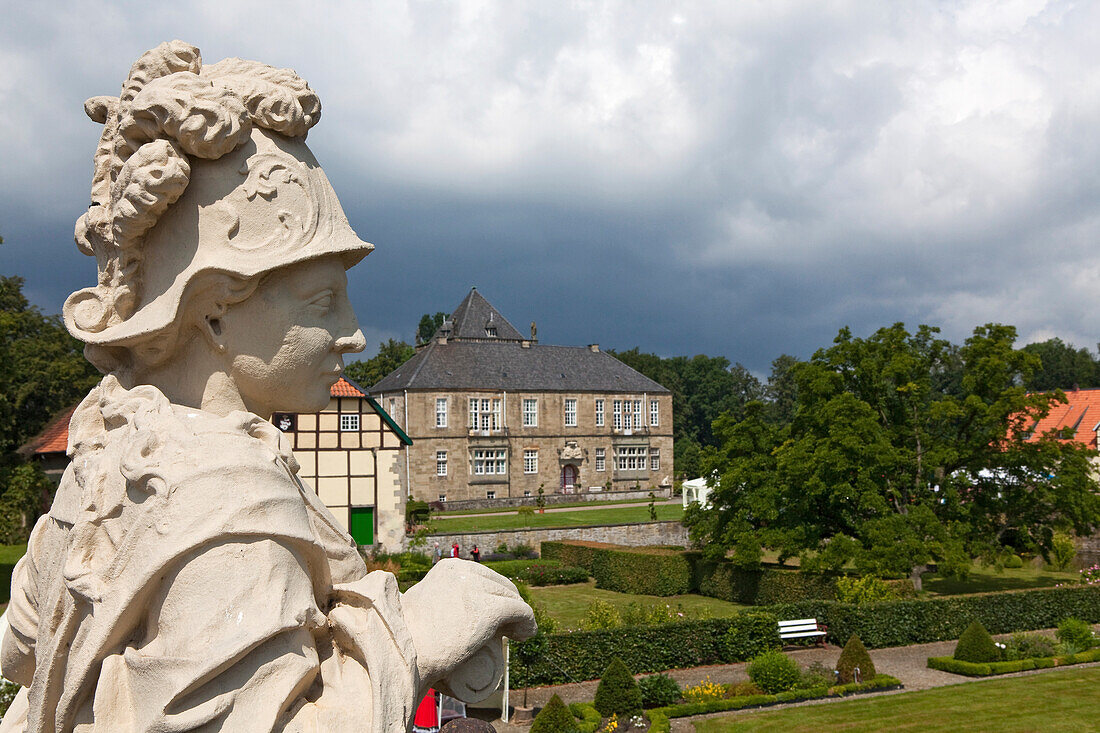 Gesmold castle and castle grounds, sculpture in the foreground, black clouds, Gesmold, Meller, Lower Saxony, Germany