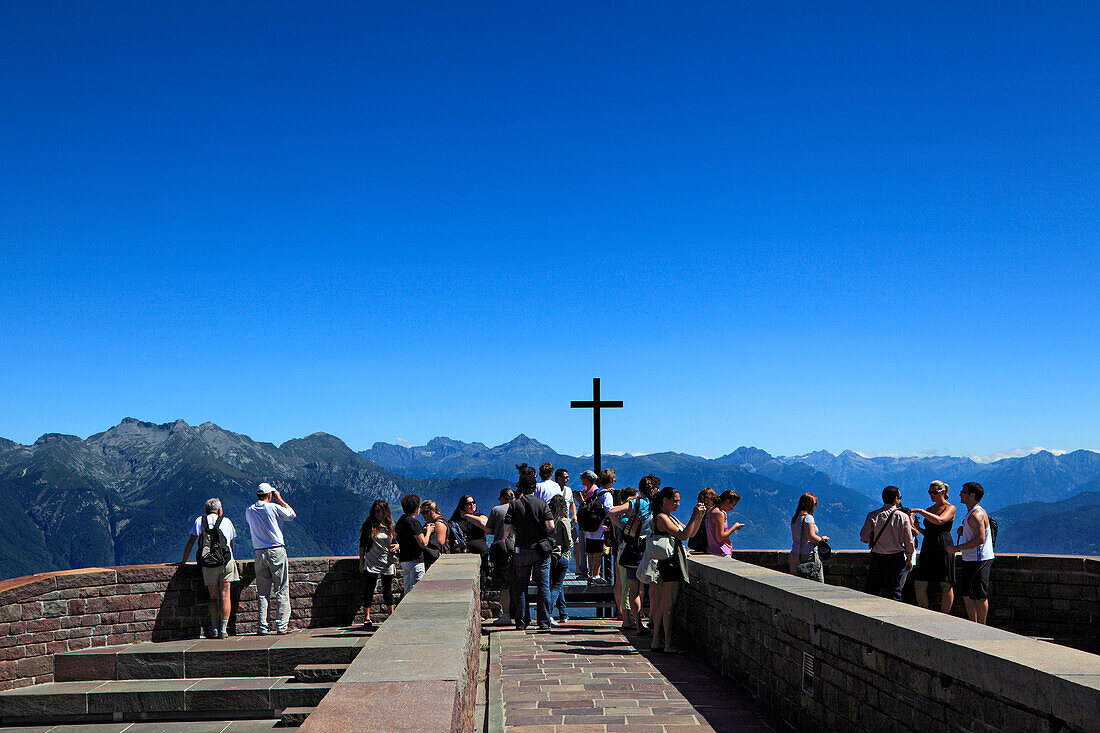Menschen vor Bergkulisse auf der Terrasse der Kapelle Santa Maria degli Angeli (Architekt: Mario Botta), Alpe Foppa, Bergwanderung zum Monte Tamaro, Tessin, Schweiz
