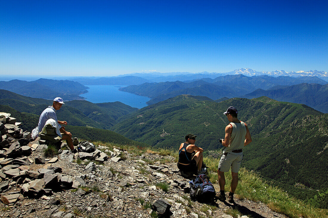 Hikers having a rest at the mountain top of Monte Tamaro, view to Lago Maggiore, hike in the mountains to Monte Tamaro, Ticino, Switzerland