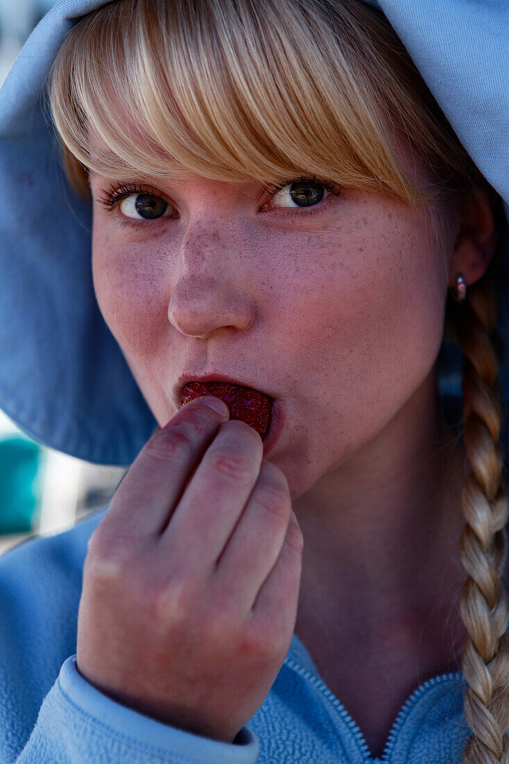 Young girl eating a strawberry at the market, Turku, Finland