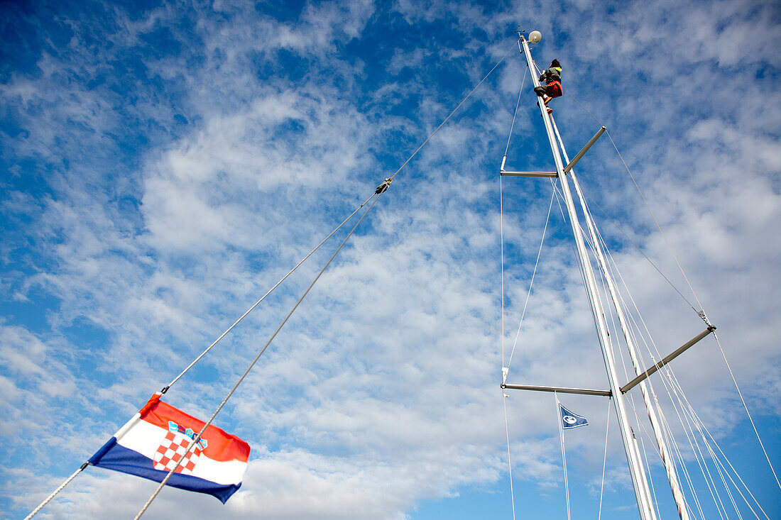 Sailor at the mast of a sailingboat under clouded sky, Kornati archipelago, Croatia, Europe