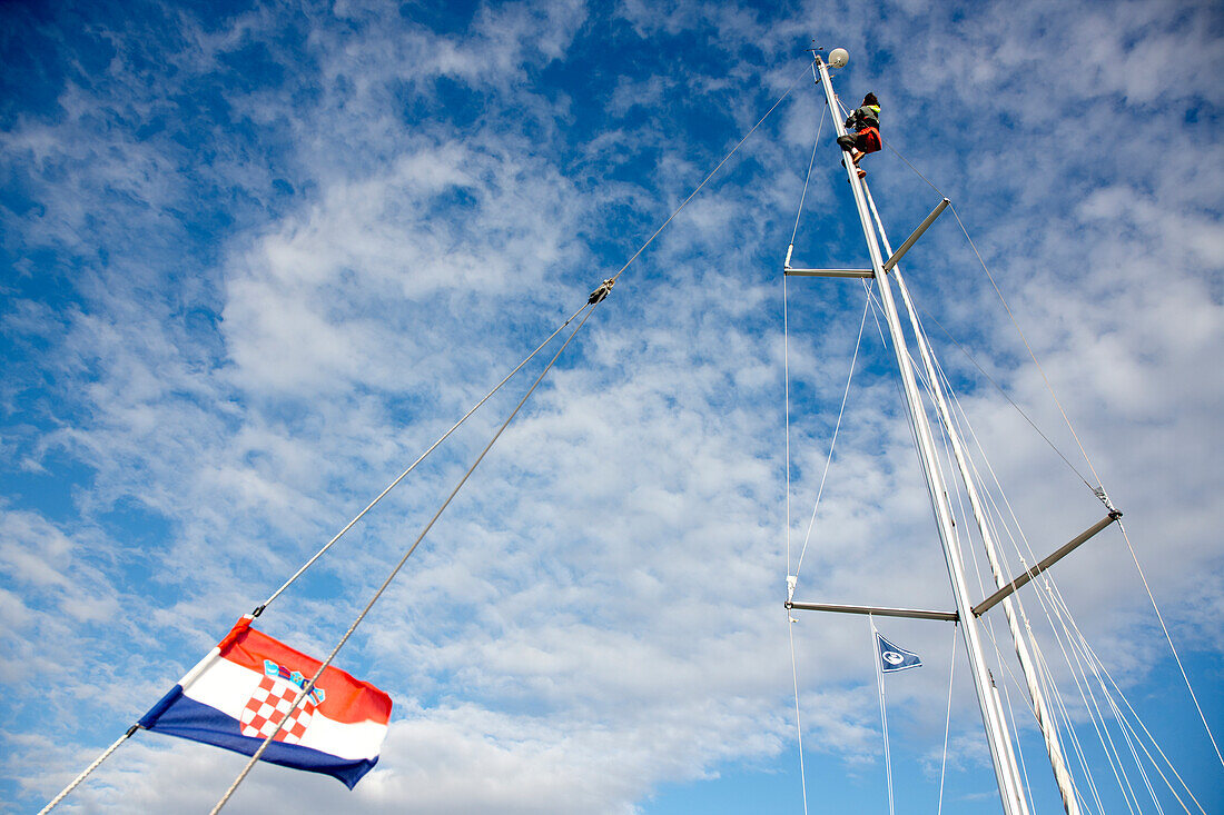 Segler am Mast einer Segelyacht unter Wolkenhimmel, Kornaten, Kroatien, Europa