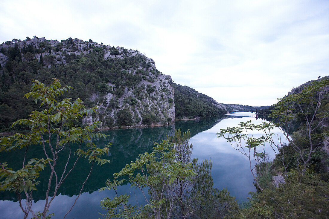 Fluss und Uferlandschaft unter Wolkenhimmel, Kroatien, Europa