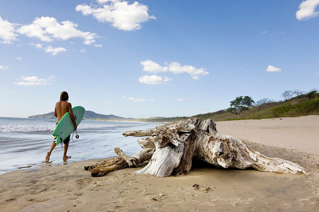 Surfer walking on the shore of Playa Grande in Costa Rica