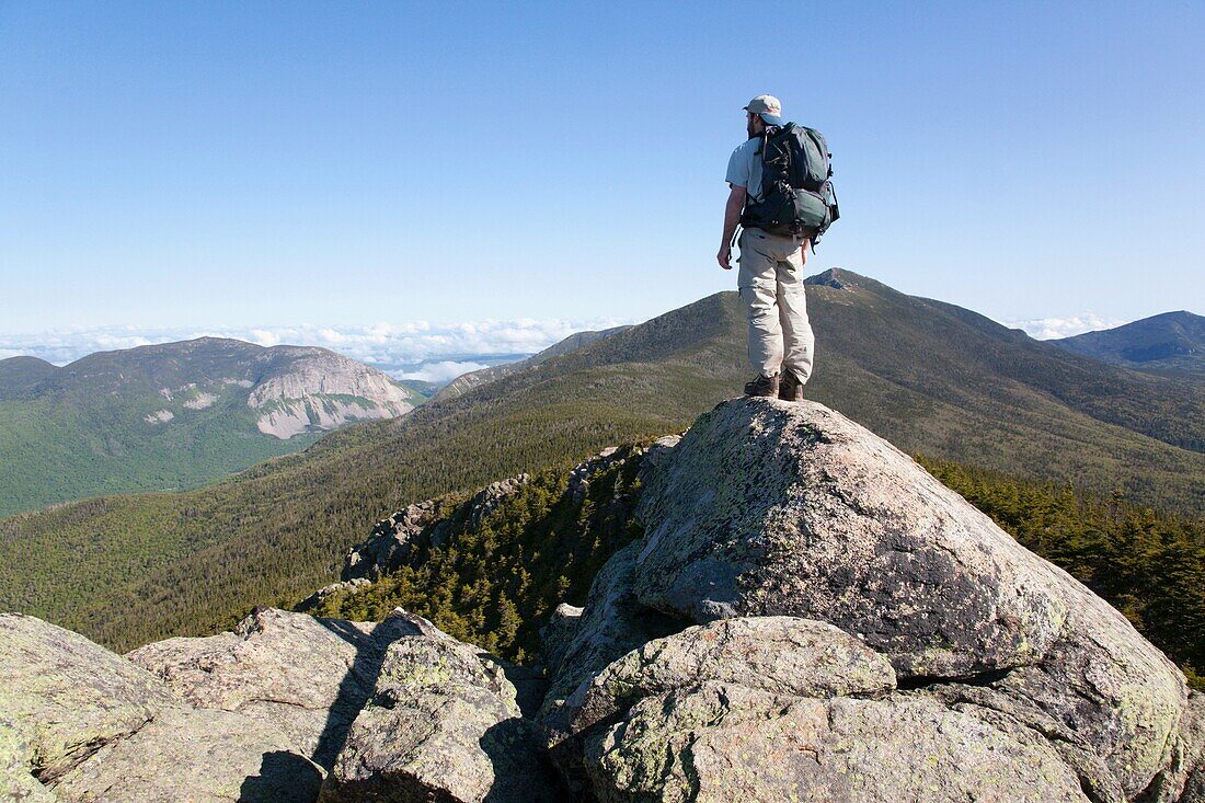 A hiker takes in the views of Franconia Notch from the summit of Mount Liberty during the summer months  Located in the White Mountains, New Hampshire USA