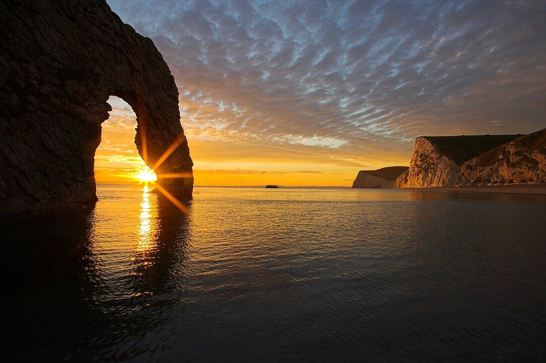 Sun setting through the Arch at Durdle Door Dorset at Sunset