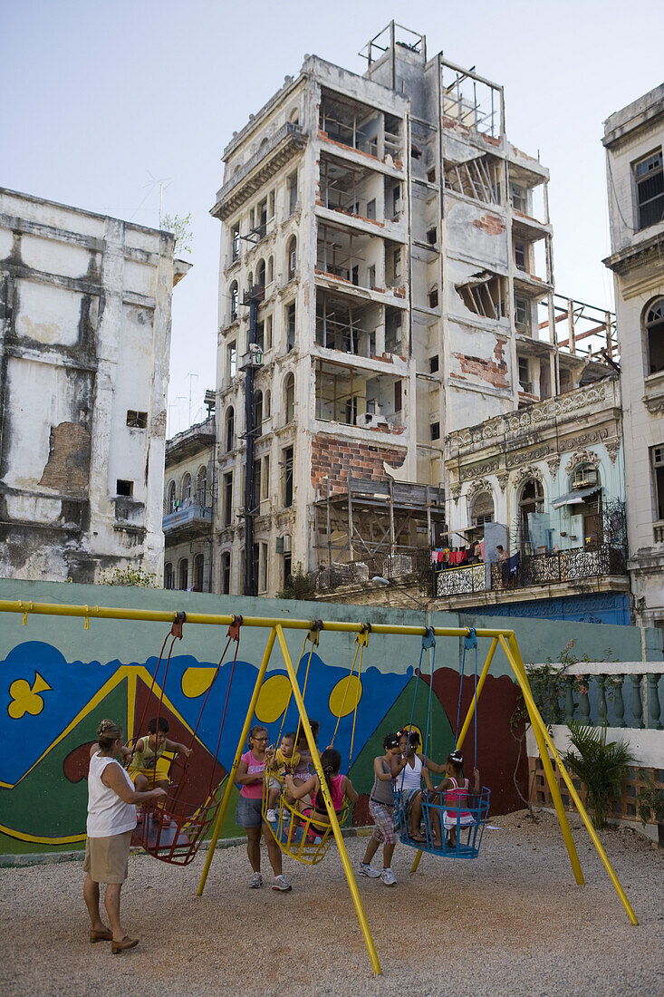 Children on swing and derelict apartment buildings, Havana, Cuba