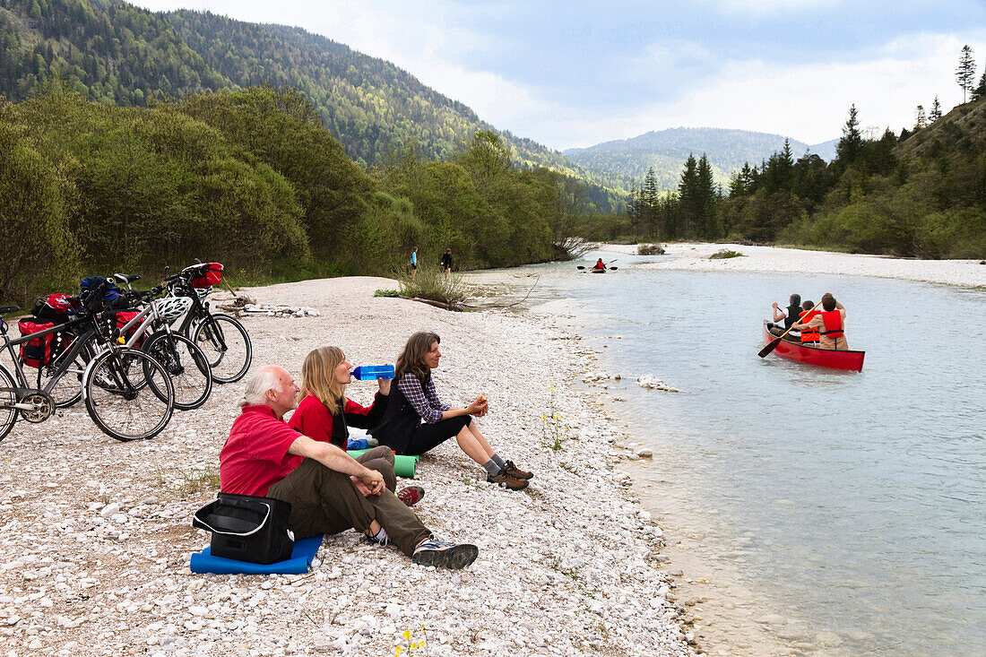 Cyclists resting at river Isar, Isar Cycle Route between Wallgau and Vorderriss, Karwendel range, Upper Bavaria, Germany