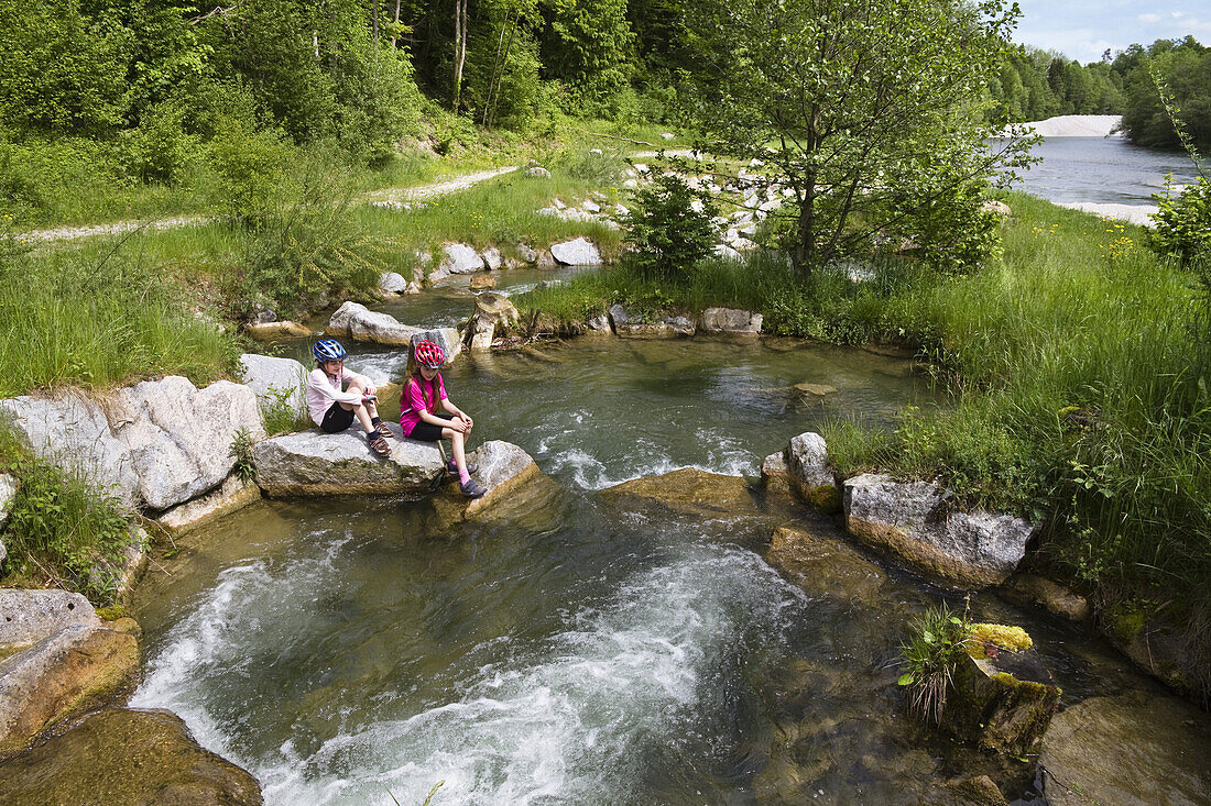 Two girls sitting on rocks in river Isar, Isar renaturation, fish-ladder near Bad Toelz, Isar Cycle Route, Upper Bavaria, Germany