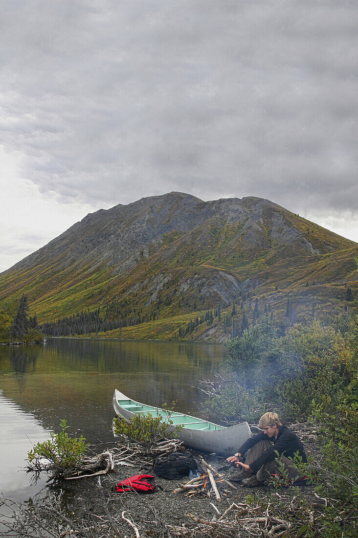 Man sitting at a campfire nwar St. Elias Lake, Kluane National Park and Reserve, Yukon Territory, Canada