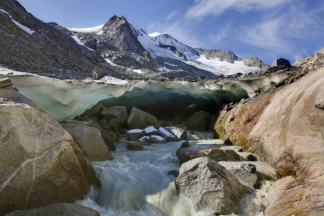 The glacier snout with ice cave of Viltragenkees in the National Park Hohen Tauern  Viltragenkees is showing signs of rapid retreat  Its snout is flat and covered with moraine The glacier foreland shows fresh moraine till  Mt Kleinvenediger in the backgro